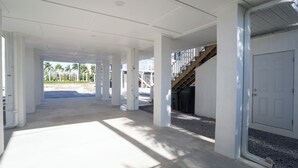 A covered outdoor area with columns, a staircase, and a door. - Charming 1/1 home across the street from the ocean sunsets, dock space included! (Bonita Springs)