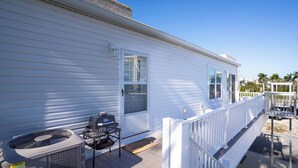 En hvid campingvogn med terrasse, grill og ventilator.