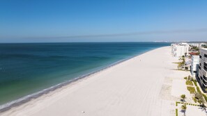 En strand med fri utsikt över havet, en sandstrand och en rad moderna byggnader med balkonger.