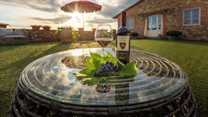 A glass table with a bottle of wine and grapes on a grassy lawn, with a stone building in the background. - Panoramic Tuscan villa with infinity pool, exclusive use, private garden (Montecarlo)