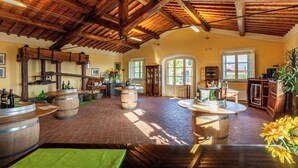 A spacious room with wooden barrel-shaped tables, a high wooden ceiling, and large windows allowing natural light. - Panoramic Tuscan villa with infinity pool, exclusive use, private garden (Montecarlo)