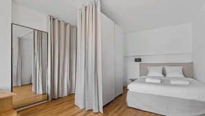 Een moderne hotelkamer met een groot bed, een nachtkastje, een spiegel en een houten vloer.