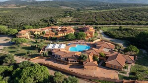 An aerial view of a resort with multiple buildings, a swimming pool, and surrounding greenery. - Cozy Accommodation With Shared Pool (Aglientu)