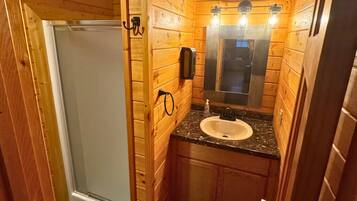 Een badkamer in chaletstijl met een wastafel, spiegel en handdoekhouder.