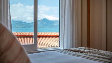 A bedroom with a view of a coastal landscape through a window.