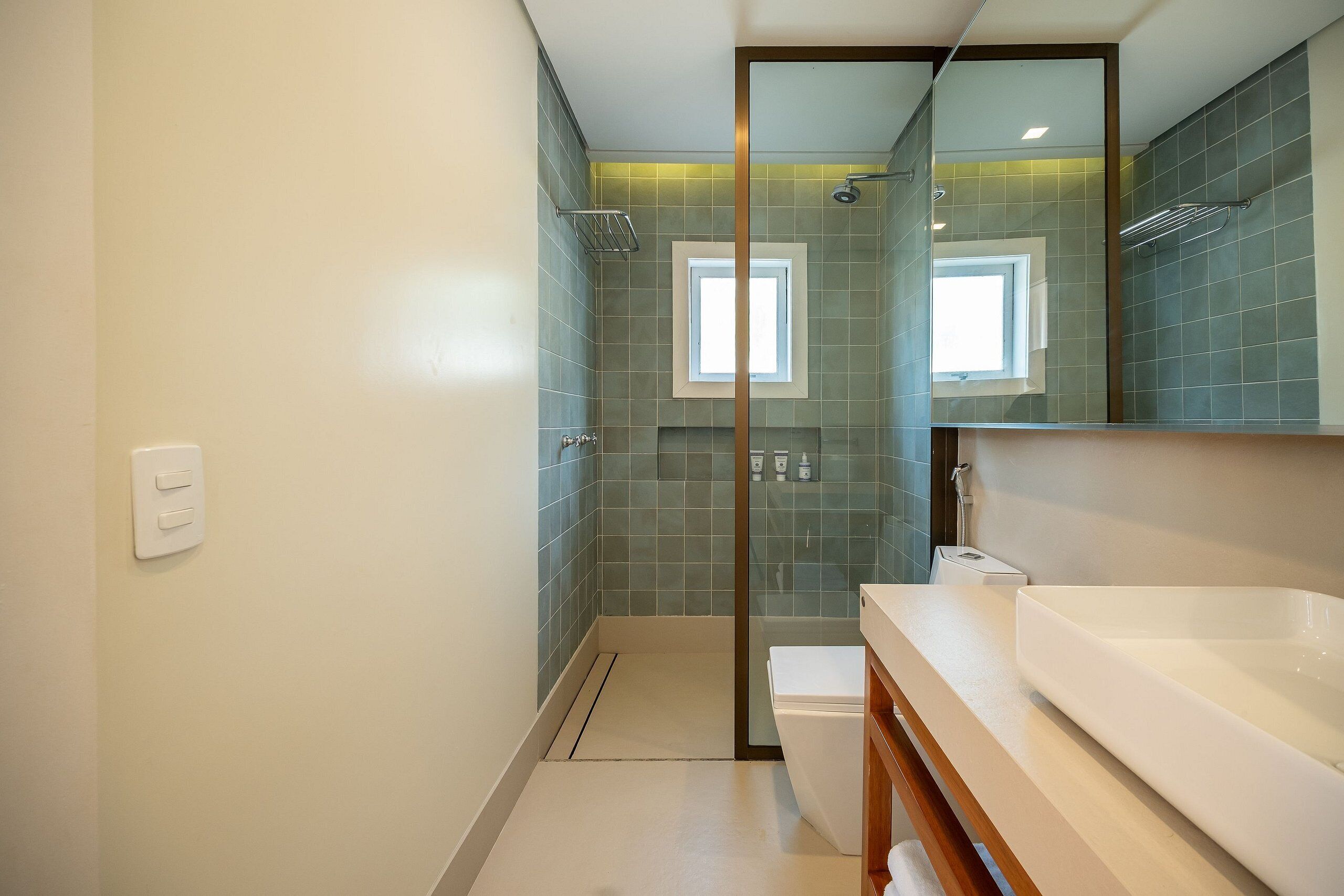 Een moderne badkamer met een douchecabine van glas, een groot, wit bad en een wastafel met spiegel.