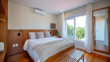 A modern bedroom with a wooden bed, a large window with a view of palm trees, and a wooden bench.