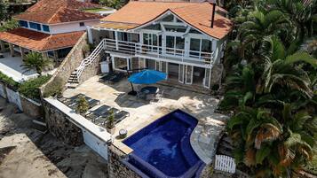 A two-story house with a swimming pool, stone walls, and a patio area.
