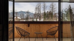 A balcony with two wicker chairs and a small table, overlooking a snowy mountain landscape. - Butorowy Residence Kościelisko by Downtown Apartments (Kościelisko)
