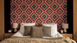 A bed with white linens and multiple pillows, a fluffy beige rug, and a patterned wall behind. - Butorowy Residence Kościelisko by Downtown Apartments (Kościelisko)