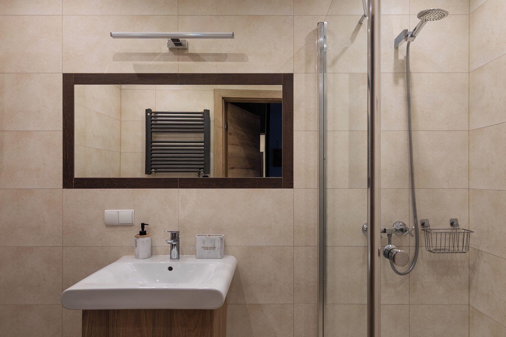 Uma casa de banho moderna com uma pia branca, um espelho, um porta-toalhas e um chuveiro com acessório de mão.