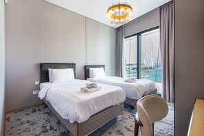 Ein Hotelzimmer mit zwei Betten, einer Kandelaber, Blick auf ein Riesenrad und einem großen Fenster.