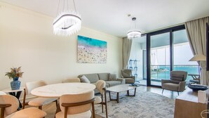 A modern living room with a round dining table, sofas, and a view of the sea through large windows. - Full Sea View!, 2br in JBR (Dubai)