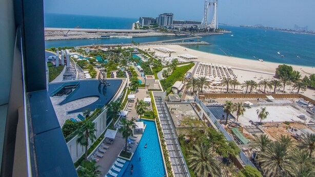 A resort with a pool, beach, and a Ferris wheel in the background. - Full Sea View!, 2br in JBR (Dubai)