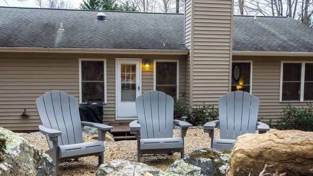 Two Adirondack chairs in front of a house with a door and windows. - Spacious 4BR Retreat w/Free Tix | Fire Pit + Grill (Asheville)
