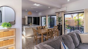 A modern kitchen with a dining area, a sofa, and a view of the outdoor patio. - Bay View Home with Rooftop & Private Pool (El Centenario)