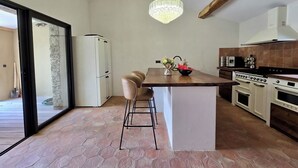Eine Küche mit einer Kochinsel, Holzbalken, einem Kronleuchter und einem Kühlschrank.