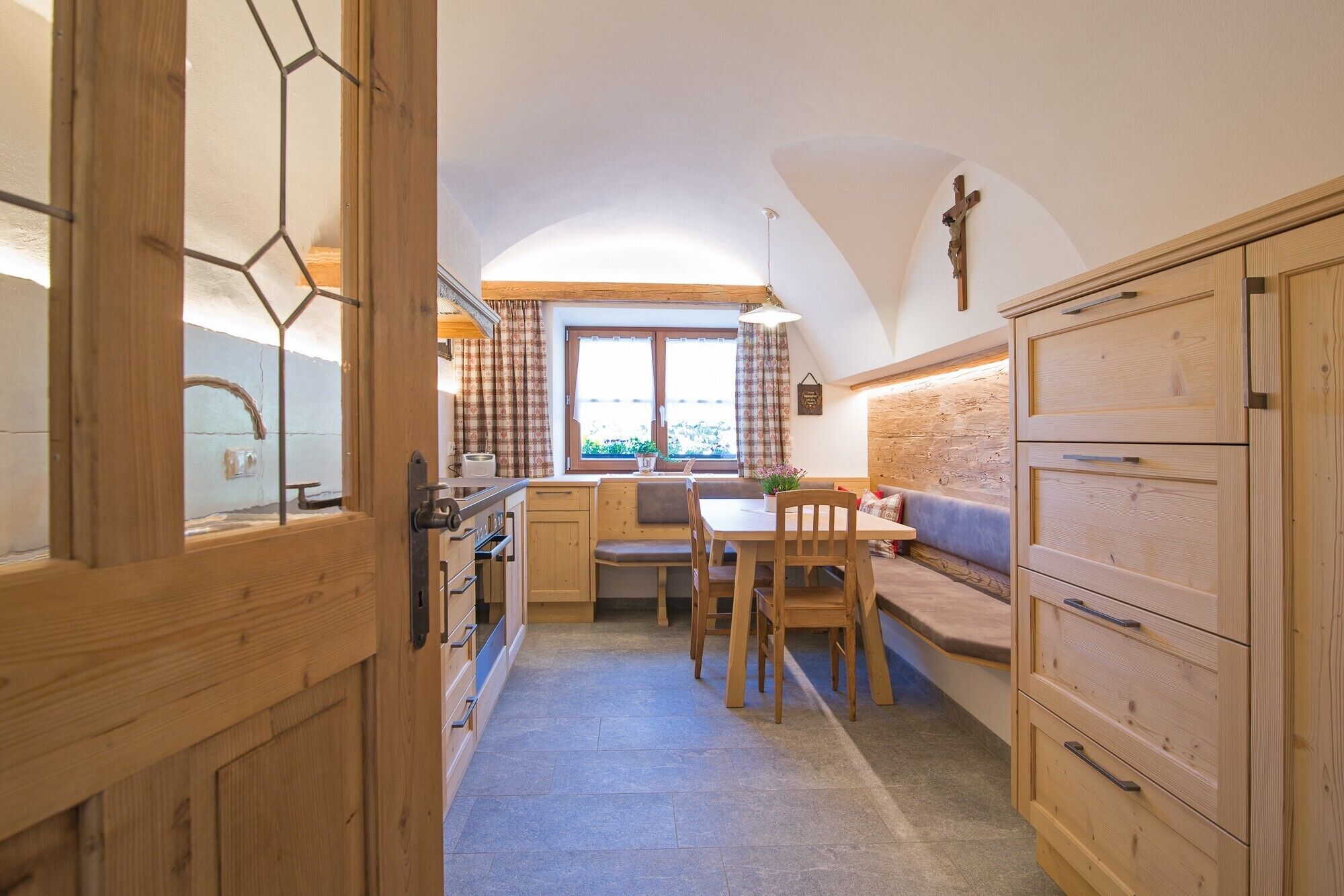 A cozy kitchen with wooden cabinets, a dining table, and a bench.