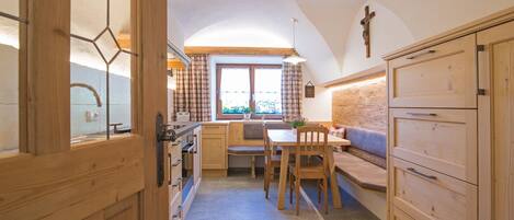 A cozy kitchen with wooden cabinets, a dining table, and a bench.