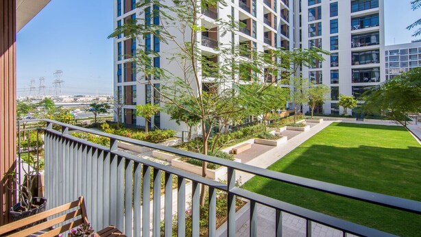 Um edifício de apartamentos moderno com várias varandas, um gramado bem cuidado e vista para a cidade.