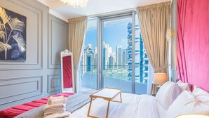 A hotel room with a bed, a small table, a city view, and a painting on the wall. - Marina View- 1br in Stella Maris (Dubai)