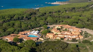 Eine Vogelperspektive eines Küstenwohngebiets mit Häusern, einem Swimmingpool und freiem Blick auf das Meer und entfernte Berge.