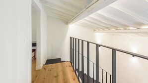 A staircase with wooden steps and a black metal railing, leading to a landing with a white wall and a door. - Orcagna by MMega (Florence)