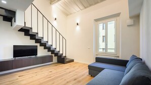 A modern living room with a staircase, a flat-screen TV, a grey sofa, and a window with a view. - Orcagna by MMega (Florence)