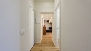 A narrow hallway with wooden flooring and white walls, leading to a staircase and a kitchen area. - Orcagna by MMega (Florence)
