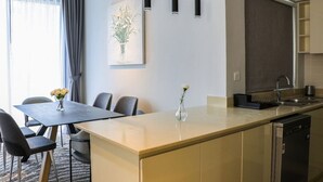 A modern kitchen with a central island, a dining area with chairs, and a painting on the wall. - 4BR + Maids Villa in Maple 2, Dubai Hills (Dubai)