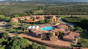 An aerial view of a resort with multiple buildings, a swimming pool, and surrounding greenery. - Cozy Studio With Shared Pool (Aglientu)