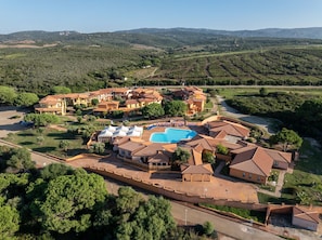A resort with multiple buildings, a swimming pool, and surrounding greenery. - Cozy Studio With Shared Pool (Aglientu)