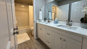 A bathroom with a walk-in shower, a double sink vanity, and a large mirror.