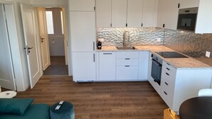 Eine moderne Küche mit weißen Schränken, einer Stein-Spritzschutzwand und einem eingebauten Backofen.