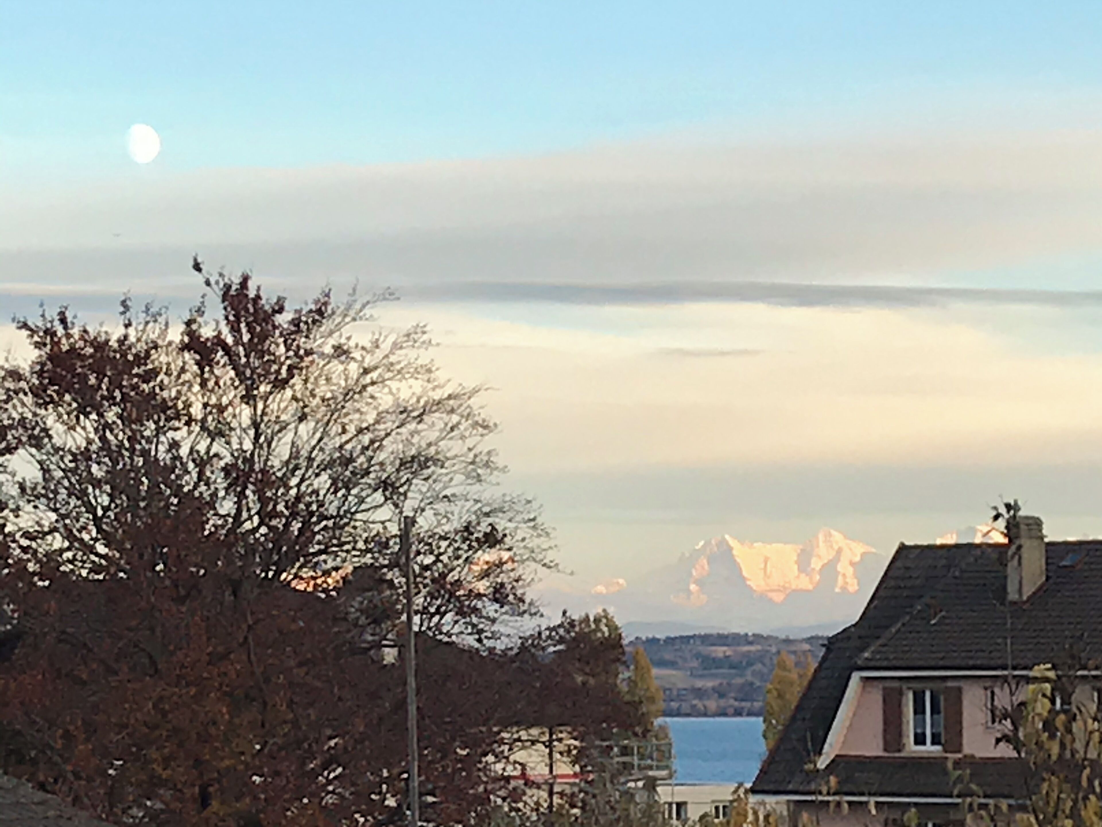 Et hus med udsigt over en sø og bjerge i baggrunden.