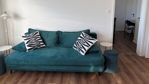 Ein Türkis-farbenes Sofa mit zwei schwarz-weißen Kissen, zwei runden Beistelltischen und einem Holzboden.