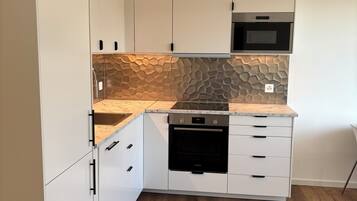 A kitchen with white cabinets, a built-in oven, and a microwave above it.
