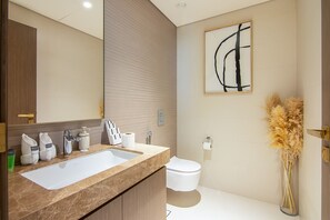 Une salle de bain moderne avec un lavabo en marbre, des toilettes et un grand miroir.