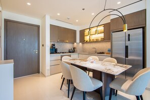 Una cocina moderna con comedor, que incluye un refrigerador de acero inoxidable grande, encimera de mármol e iluminación contemporánea.
