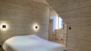 A bedroom with a bed, wooden walls, and two wall-mounted lights. - Maison Auvergnate Le repaire des Milans (Laveissière)