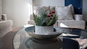 Un soggiorno con un tavolino in vetro, un divano bianco e una pianta ornamentale in vaso bianco.