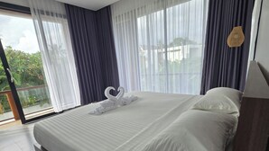 Une chambre d’hôtel avec un grand lit, des rideaux légers et une vue sur la verdure environnante.