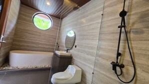 Une salle de bain moderne équipée d’une baignoire, de toilettes et d’une douche.