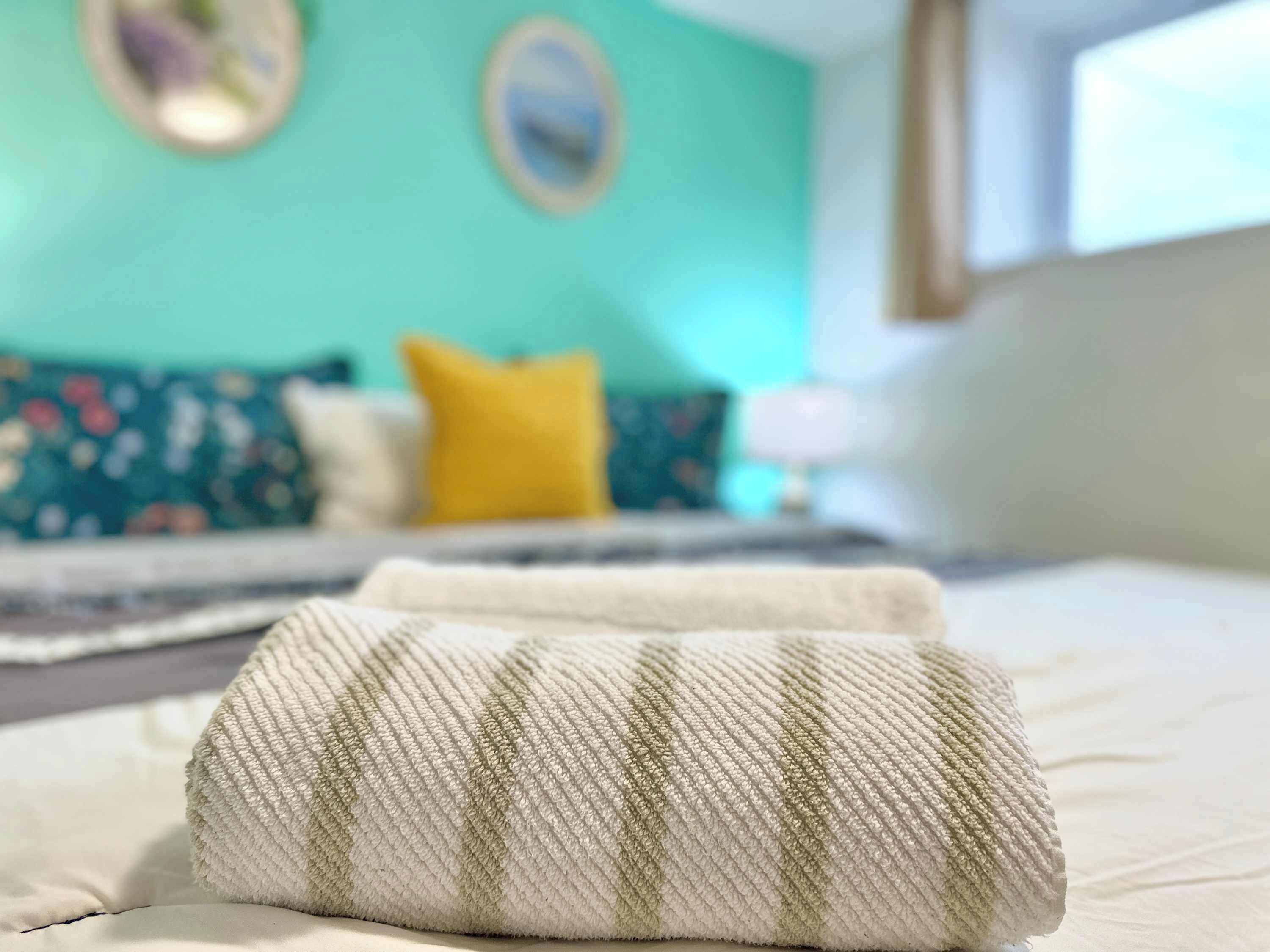Un letto con un cuscino bianco e verde a righe e una parete color acquamarina con un cuscino giallo sullo sfondo.