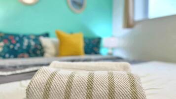 Un letto con un cuscino bianco e verde a righe e una parete color acquamarina con un cuscino giallo sullo sfondo.