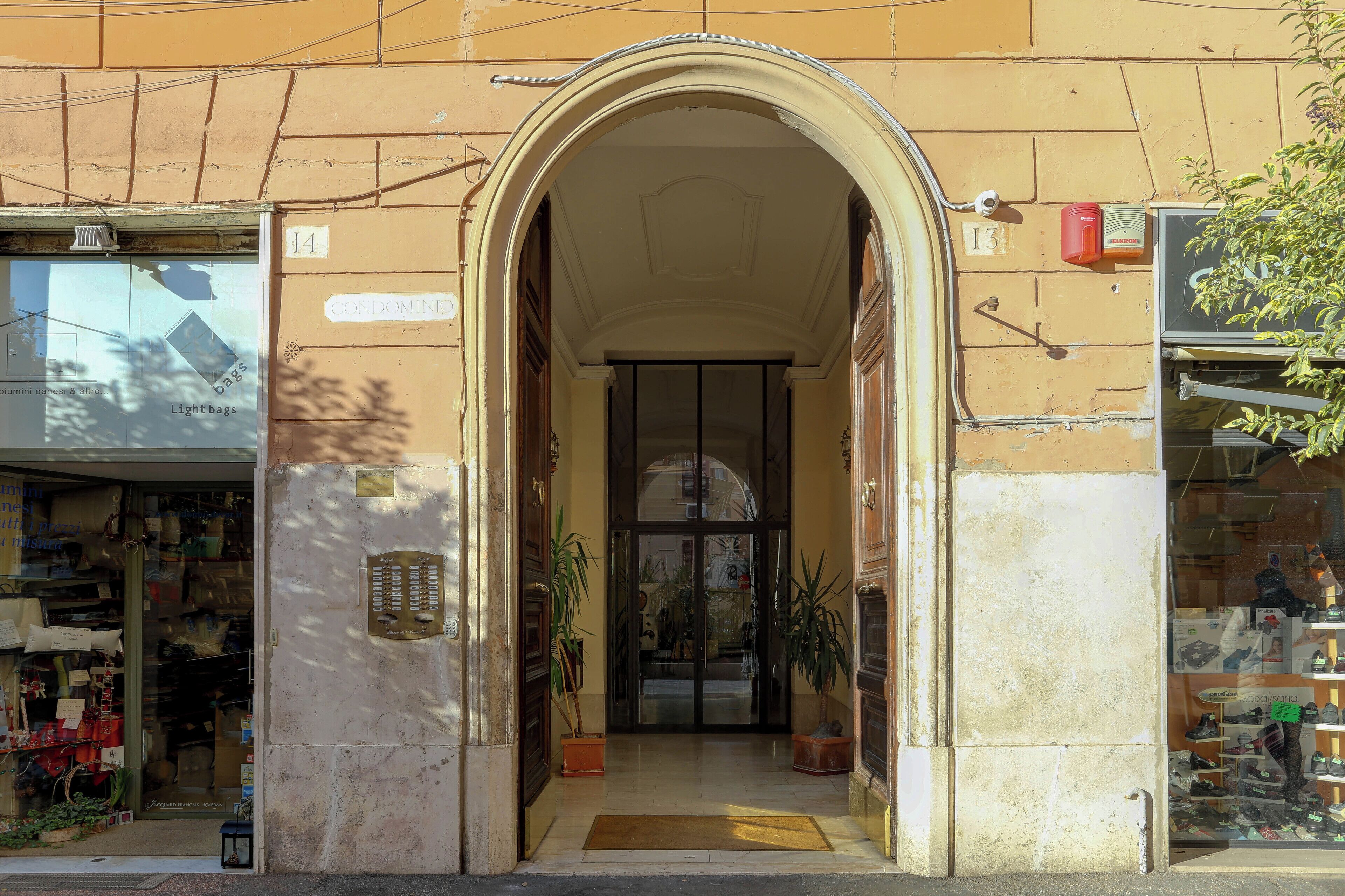 An entrance with a large archway, a door with glass panels, and potted plants.