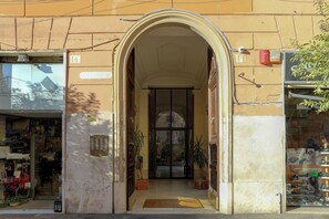 An entrance with a large archway, a door with glass panels, and potted plants. - Rione Prati Boutique Suites (Rome)