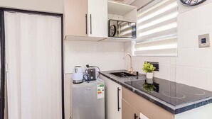 Una cocina compacta equipada con nevera, tostadora, hervidor y pileta.