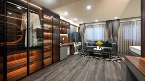 Een moderne woonkamer met een bank, salontafel en een televisie. Er is een houten kast met een spiegel en een kapstok.