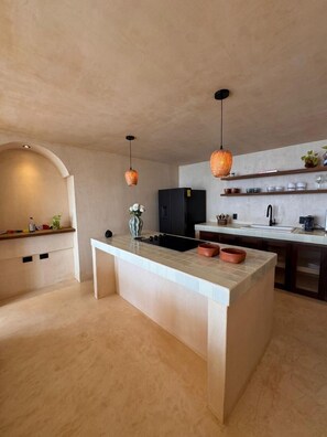 A modern kitchen with a central island, pendant lights, and a built-in oven. - Sea Breeze Penthouse at Conchas Chinas (Puerto Vallarta)